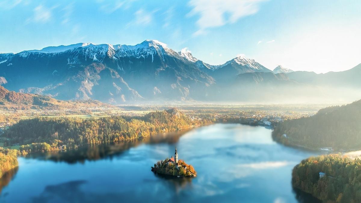 Vue aérienne d'un lac avec une petite île et une église, montagnes enneigées