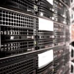 Baie de serveurs informatiques noirs en rack avec technicien intervenant sur équipements