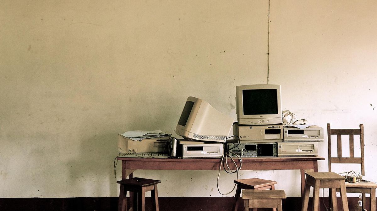 Anciennes machines informatiques empilées sur table, chaises, mur Anciennes machines informatiques empilées sur table, chaises, mur