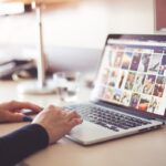 Une main tapotant le clavier d'un ordinateur affichant des photos