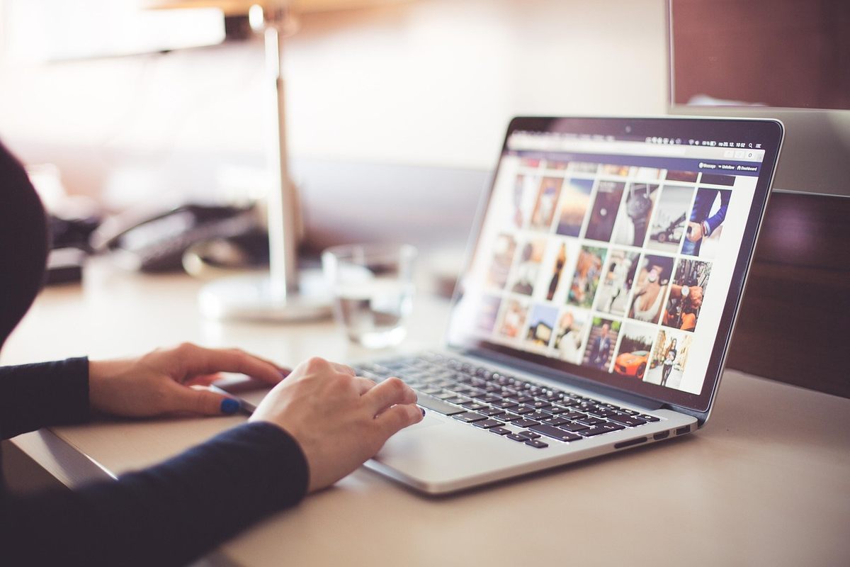 Une main tapotant le clavier d'un ordinateur affichant des photos