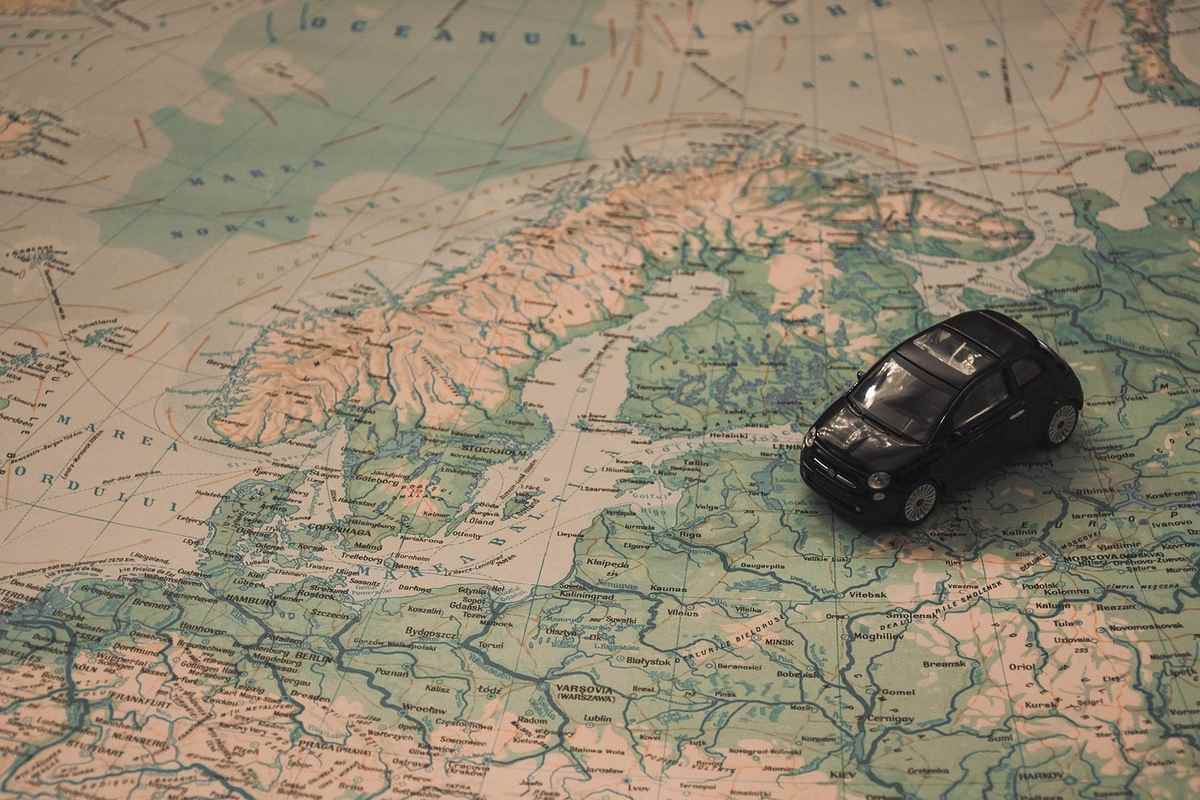 Une petite voiture noire posée sur une carte géographique détaillée Une petite voiture noire posée sur une carte géographique détaillée